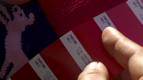 4k macro shot of fashion designer comparing sock color to pantone color cards