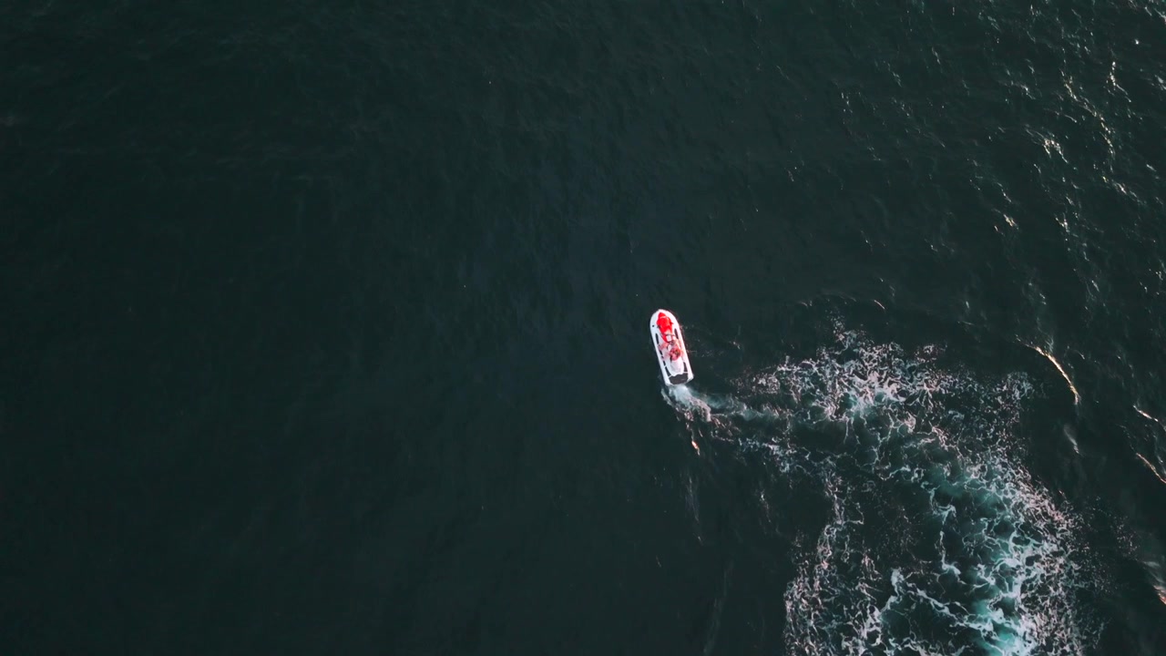 Drone view of speedboat leaving white wake across dark tropical sea