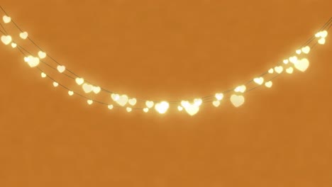 animation of  heart shaped fairy lights with copy space on orange background