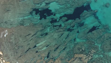 Toma-Aérea-De-Agua-Azul-Cristalina-Cerca-De-Una-De-Las-Playas-De-La-Isla-De-Cerdeña