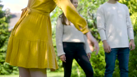 vista frontale della mano caucasica della giovane donna che lancia una palla da bocce nel parco in una giornata di sole