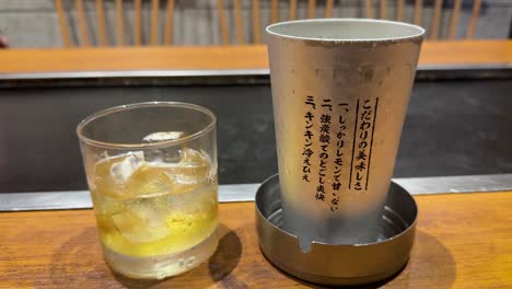 Serving-Umeshu-with-ice-in-Osaka-izakaya-bar,-metal-glass-nearby