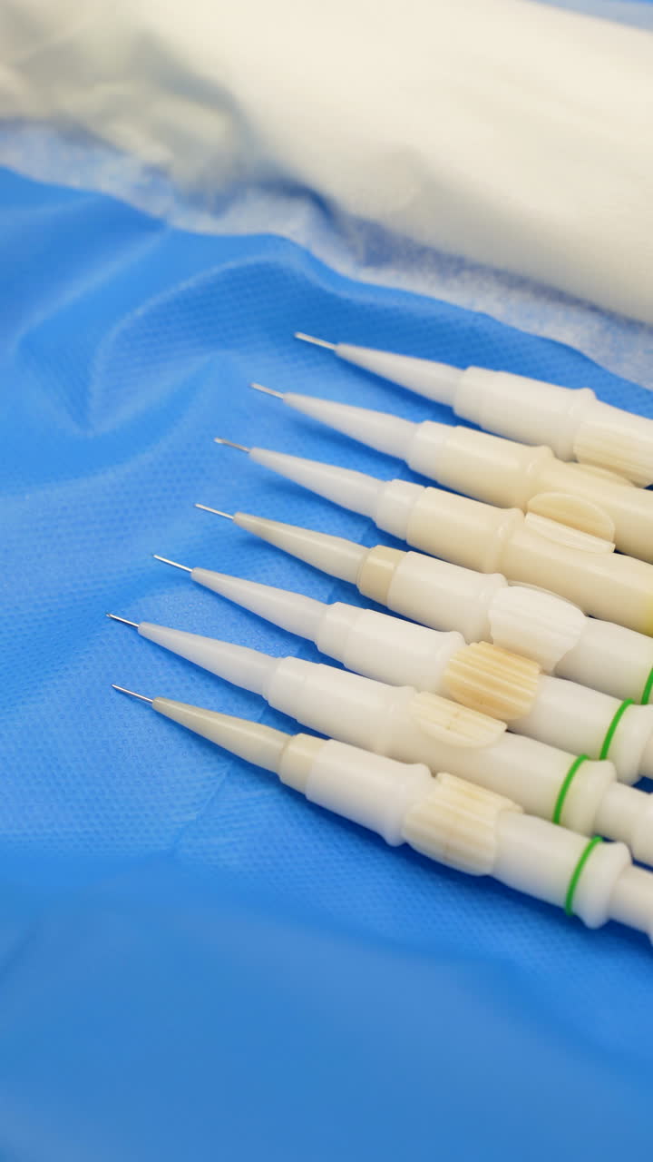 Fue implanter pens, instruments for hair follicle transplantation, resting on a sterile blue surgical drape