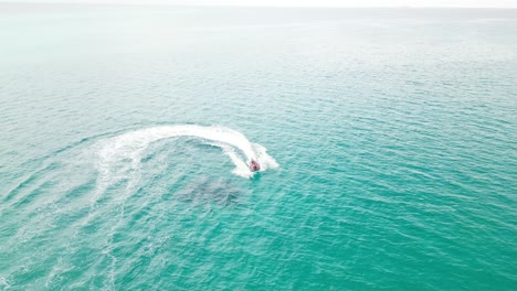 man riding jet ski fast in tropical blue water on sunny day