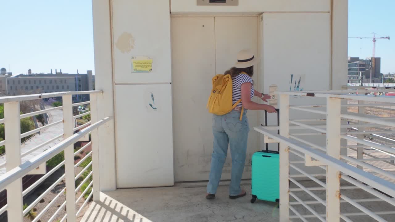 A woman is walking down a walkway with a suitcase and a backpack
