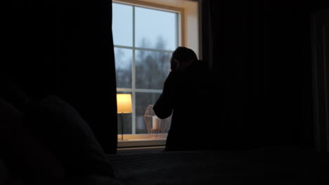 silhouetted man standing by the window in despair