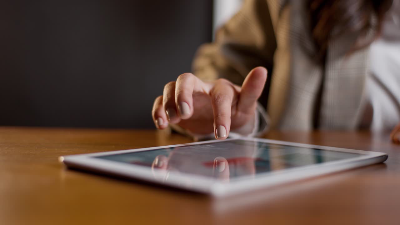Primo piano di una donna che scorre verso l'alto sullo schermo di un tablet leggendo un documento