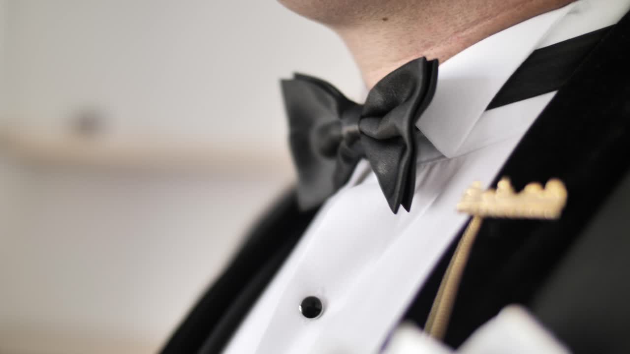 Man adjusting bow tie. Arc shot close up