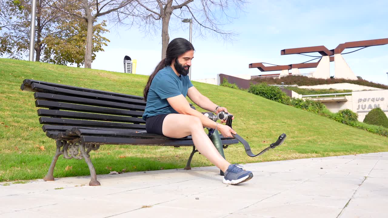 Man with prosthetic leg sitting on a bench in a park