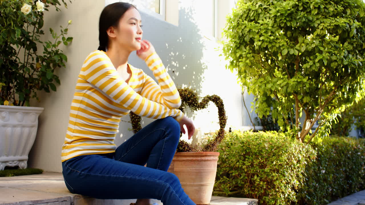 Sitting on porch, woman in striped shirt smiling and enjoying sunny day
