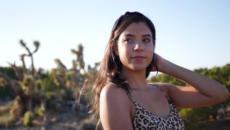 a gorgeous hispanic woman with modeling and posing with a happy smile outdoors in a desert nature landscape