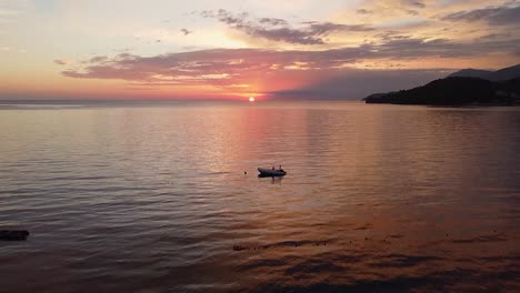 Goldene-Stunde-Am-Strand,-Ein-Atemberaubender-Sonnenuntergang-Mit-Verankertem-Boot-Und-Sonne-Am-Horizont