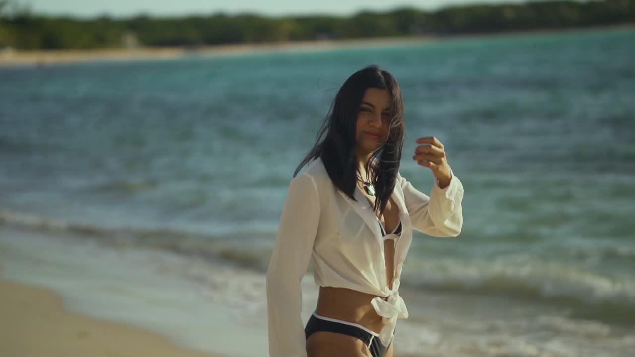 Portrait of a pretty young hispanic female model hanging around the beach smiling in the caribbean sea