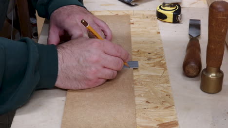 the carpenter marks the workpiece with a right angle and pencil