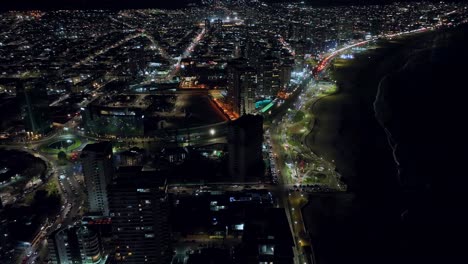 Aerial-rotating-shot-of-the-skyline-in-Iquique,-Chile-during-the-night-with-bright-lights