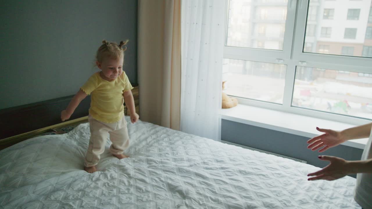 Glückliches Kleinkind rennt auf dem Bett für eine Umarmung zur Mutter