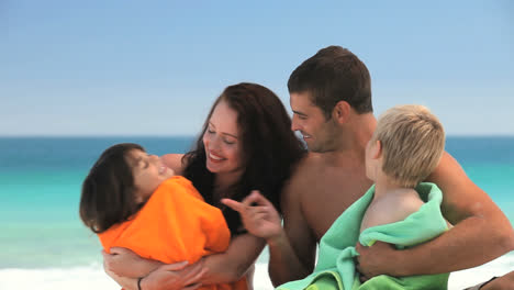 padres abrazando a sus hijos con toallas de playa