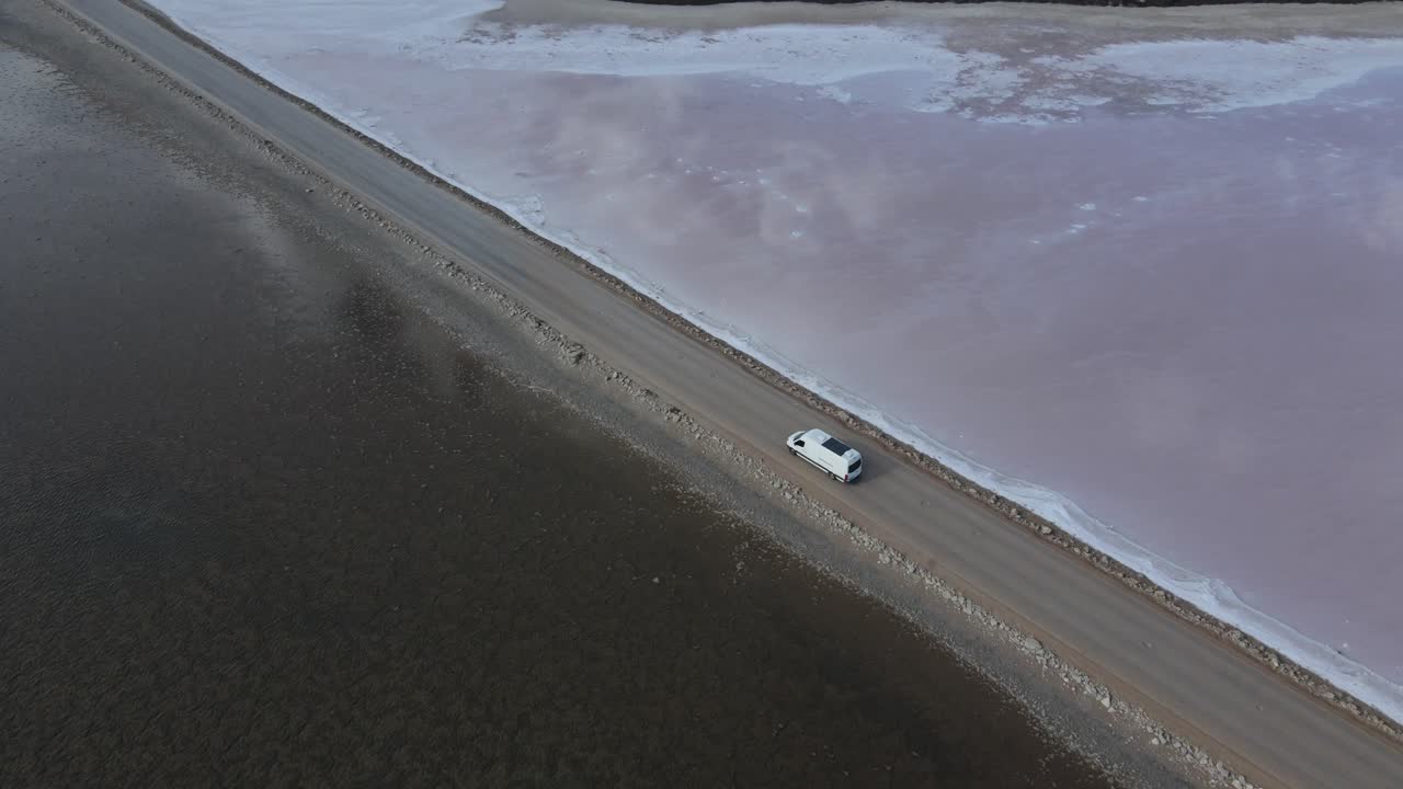 남 오스트레일리아의 핑크 레이크 맥도넬 (pink lake macdonnell) 을 가로질러 가는 캠퍼밴 위의 드론