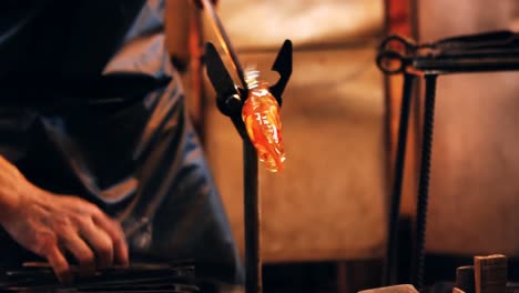 close-up of glassblower shaping a molten glass