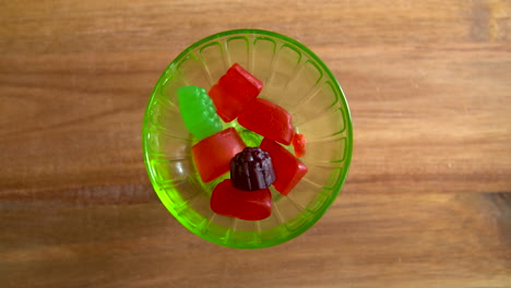 top down shot of hands taking gummy candies out of a glass dish