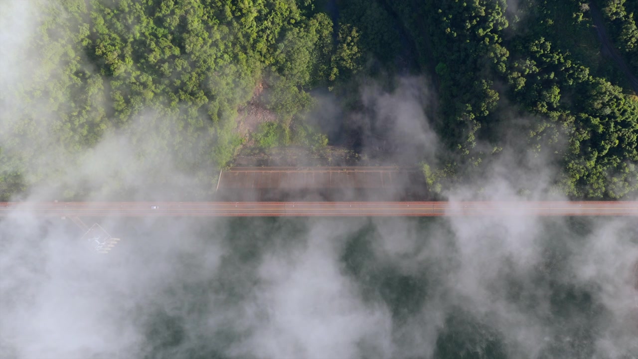 Vista aerea con drone che segue la Strada 12 attraverso la diga di Uruguai mentre nuvole basse si muovono sulla foresta pluviale circostante