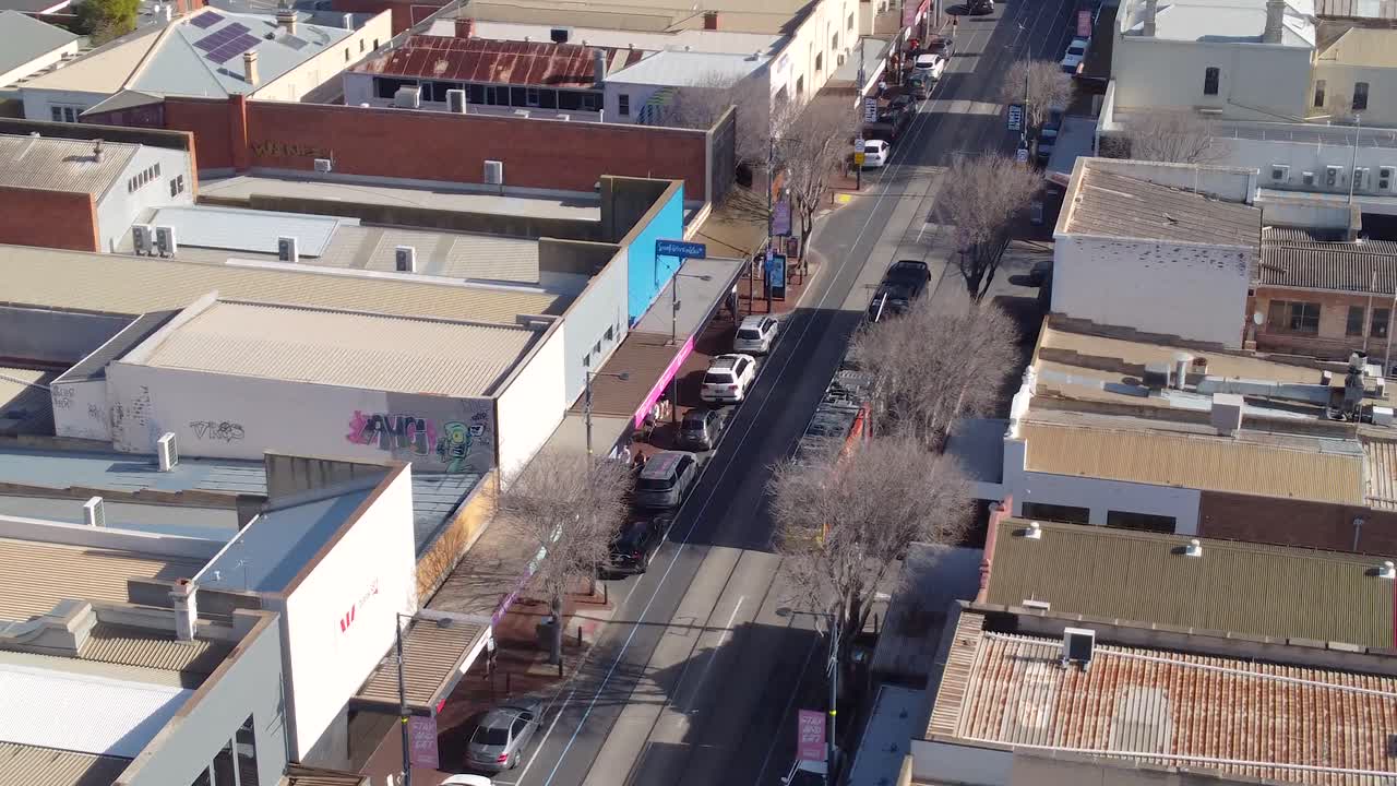Aerial view of a modern tram moving through the Glenelg shopping district in Adelaide, Australia. This footage captures the bustling energy of this popular tourist destination.