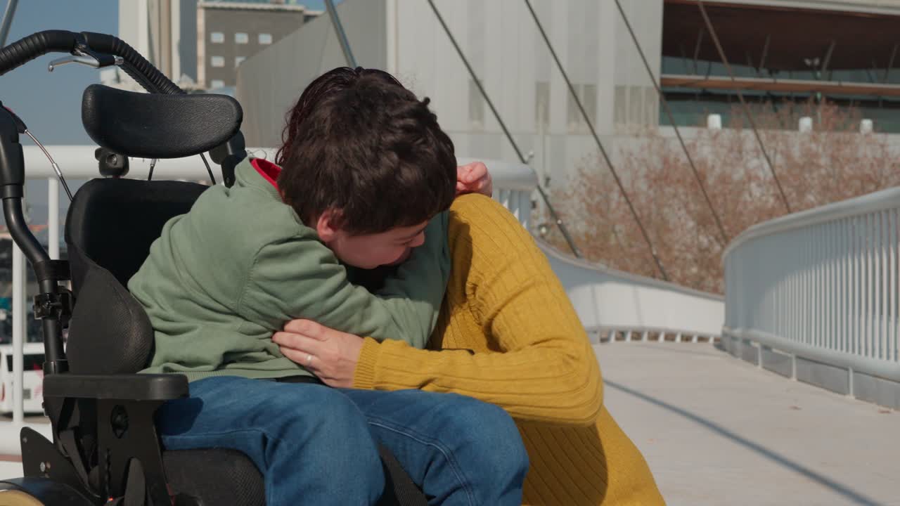 Mother embracing disabled son in wheelchair on bridge