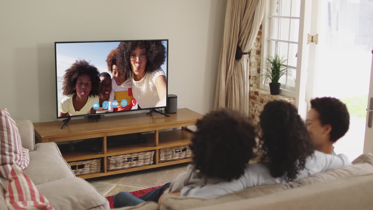 Famiglia afroamericana che fa una videochiamata in TV mentre è seduta sul divano a casa
