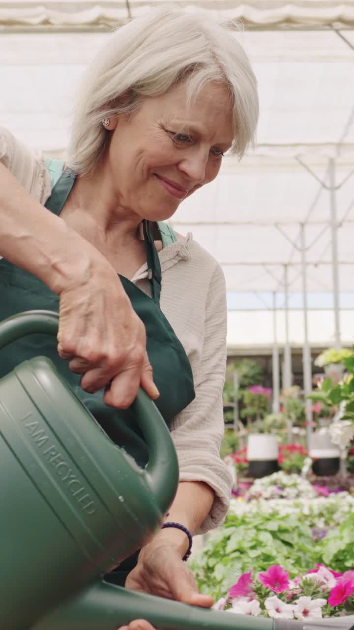 여성 이 온실 에서 식물 에 물 을 주고 있다
