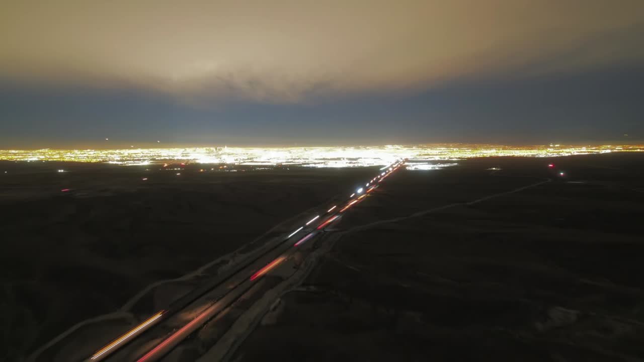 Hyper-lapse pushing in on Las Vegas at night. Drone goes over interstate as cars zoom by and the bustle of the city and nightlife can be seen in the background.