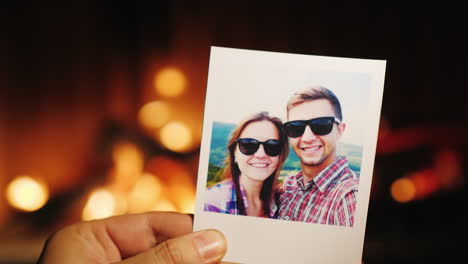 una mano sostiene una foto en llamas de una pareja joven y luego la arroja a la chimenea
