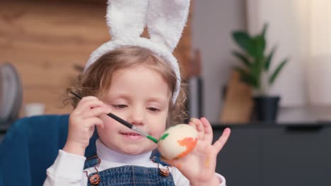 a little girl with easter bunny ears paints eggs with her family, preparing for the easter holidays. the scene captures the spirit of family fun, creativity, and the joy of the upcoming holiday