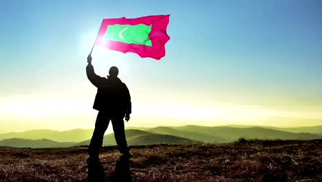 exitoso silueta hombre ganador agitando bandera de las maldivas en la parte superior del pico de la montaña, fondo de bucle cinemagraph