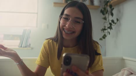 Caucasian-teenage-girl-having-video-call-while-spending-time-on-the-bedroom