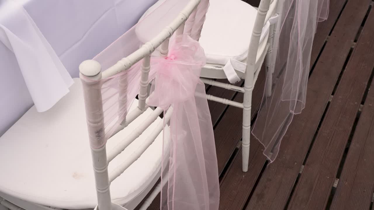 Beautifully decorated wedding chairs feature soft pink fabric drapes, adding a romantic touch to the celebration. This setup creates a dreamy atmosphere for guests