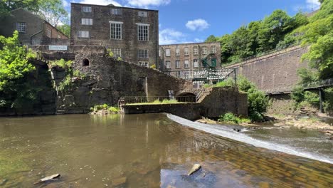 river scene with old mill and a walkway, with the river falling over a small waterfall