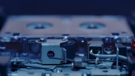 exposed internal components of microcassette recorder playing under cold blue lighting