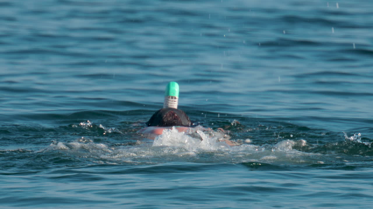 A man wearing a full face snorkel mask floats calmly on the surface of the Mediterranean Sea