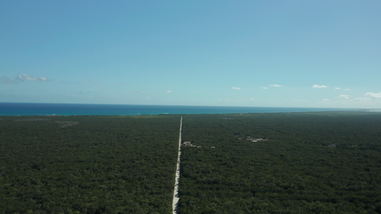 이 드론 샷은 마야 정글과 멕시코 툴룸의 캐리비안 바다로 이어지는 긴 도로 사이의 극명한 대조를 보여줍니다.