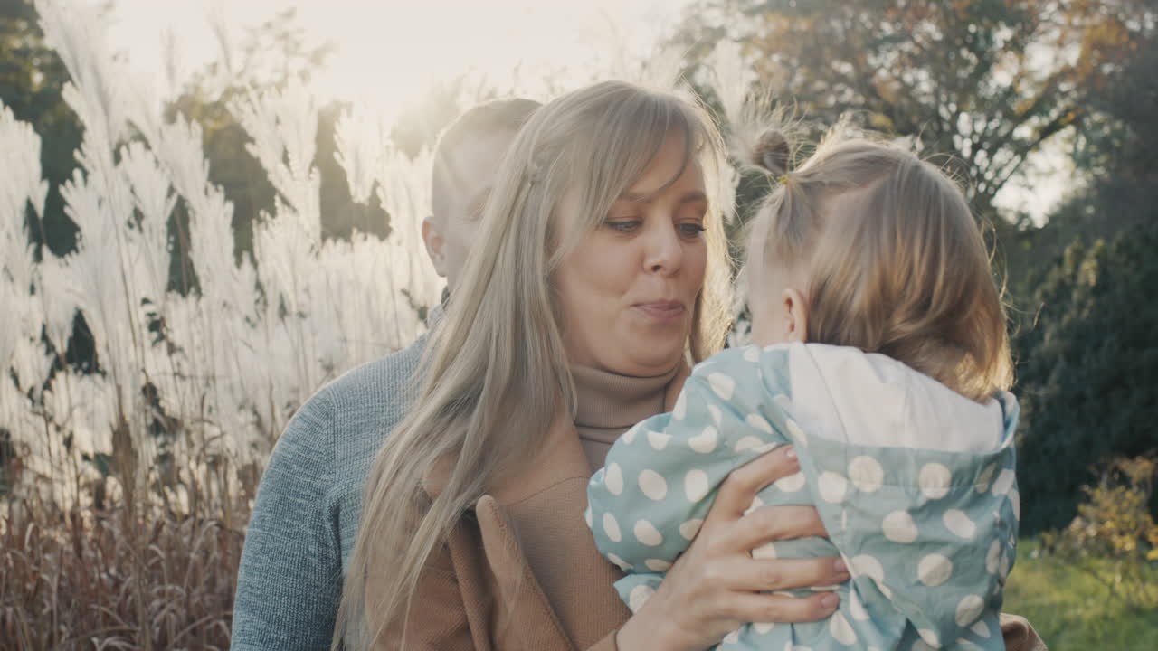 행복한 부모 부부가 공원에서 어린 딸과 함께 놀고 웃고 함께 즐거운 시간을 보내고 있습니다.