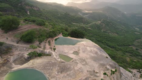Vista-Aérea-De-Cataratas-Petrificadas-En-Las-Montañas-Al-Atardecer,-Hierve-El-Agua,-México