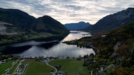 Alpes-Austríacos-Grundlsee-Lago-Cristalino-Rodeado-De-Exuberantes-árboles-Verdes-Y-Montañas-Bajo-Un-Cielo-Azul-Claro-Con-Algunas-Nubes-Blancas,-Capturado-Desde-Un-Punto-De-Vista-Aéreo