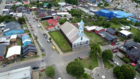 aerial drone fly above dalcahue city streets chiloé chile patrocinio lady church during daylight, panoramic establishing shot