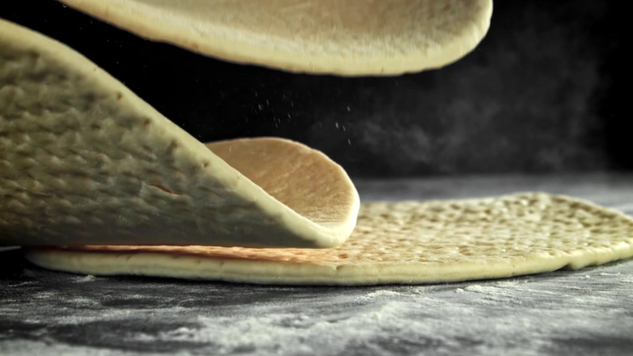 Impasto fresco per pizza che cade e si impila su una superficie infarinata