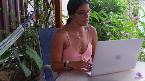 Hispanic-woman-digital-nomad-works-with-laptop-computer-on-warm-deck