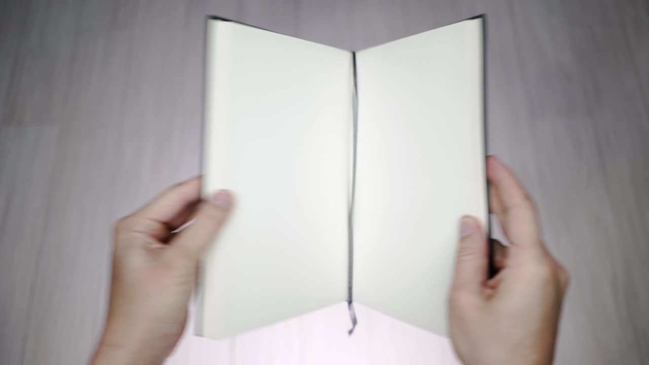 Blank textbook opening with hands.