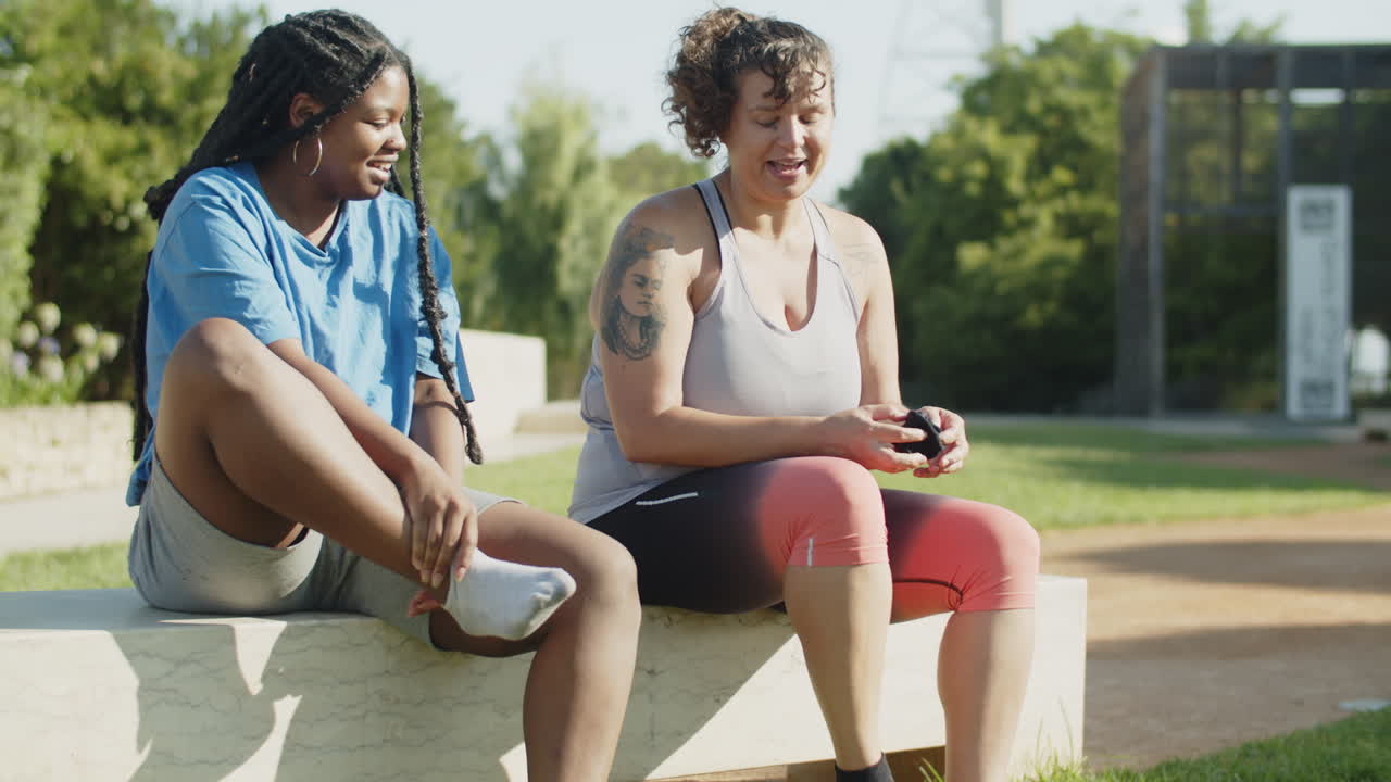 Happy friends wearing socks and laughing after training in park