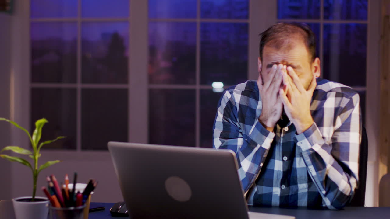 Stressed man working late at night on a laptop