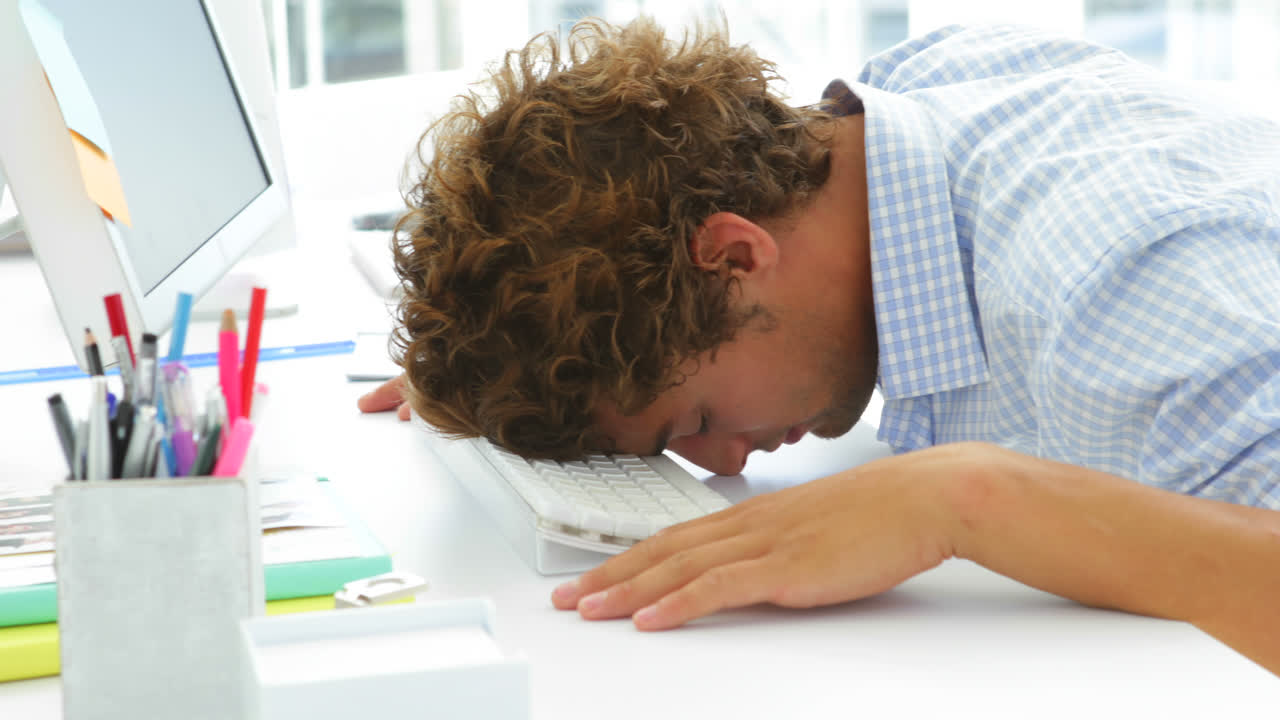 Utmattet forretningsmann sover med hodet på tastaturet