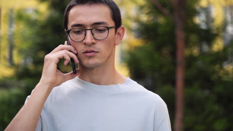 屋外の通りに立っている間携帯電話で話している深刻な若い日本人男性 1